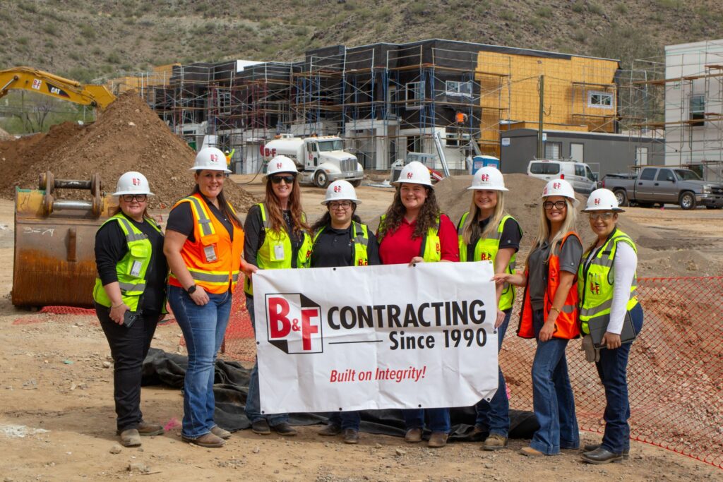 B&F ladies posing with logo banner in a job site