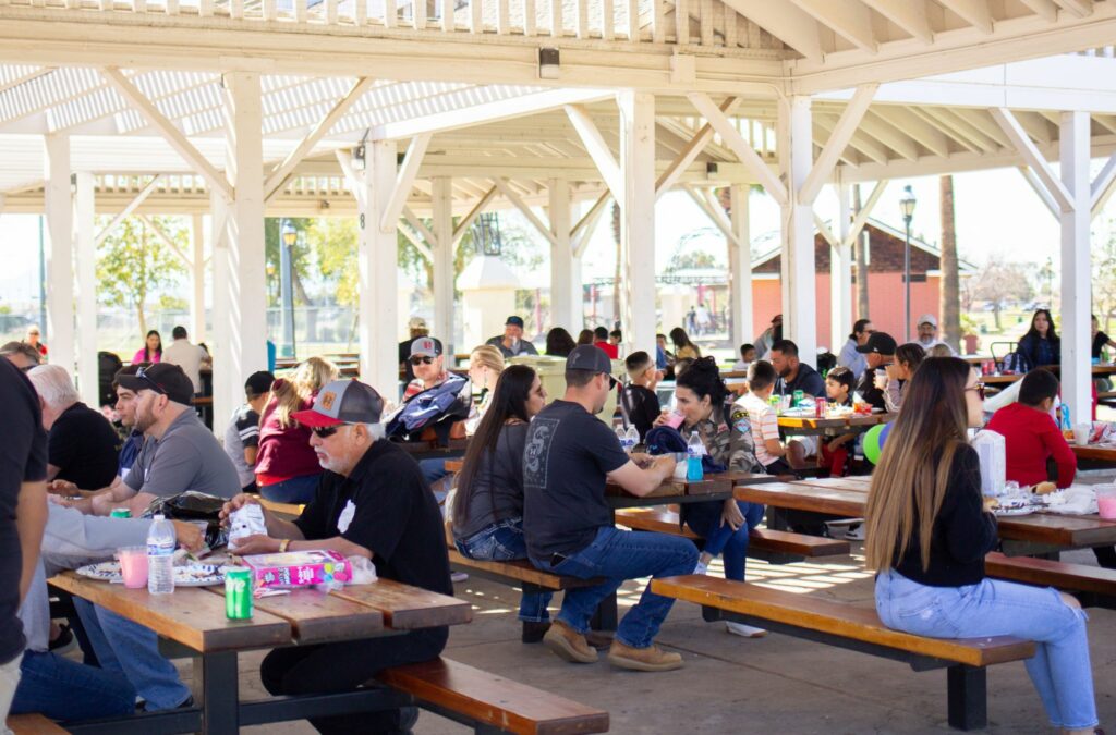 People sitting eating on picnic tables