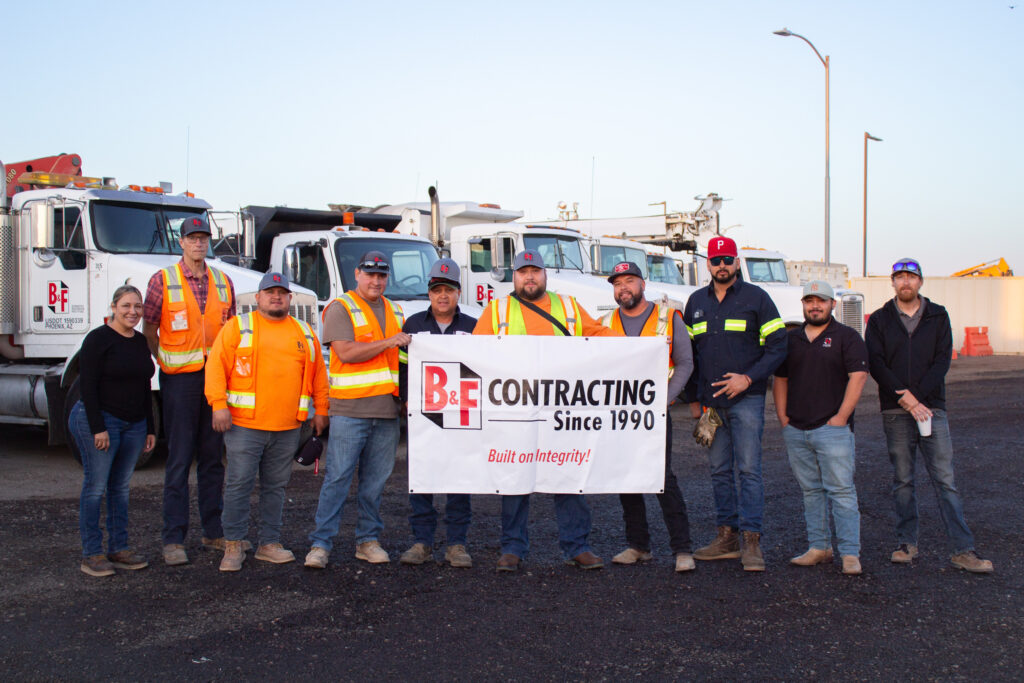 Truck drivers and safety department staff posing with a B&F banner.