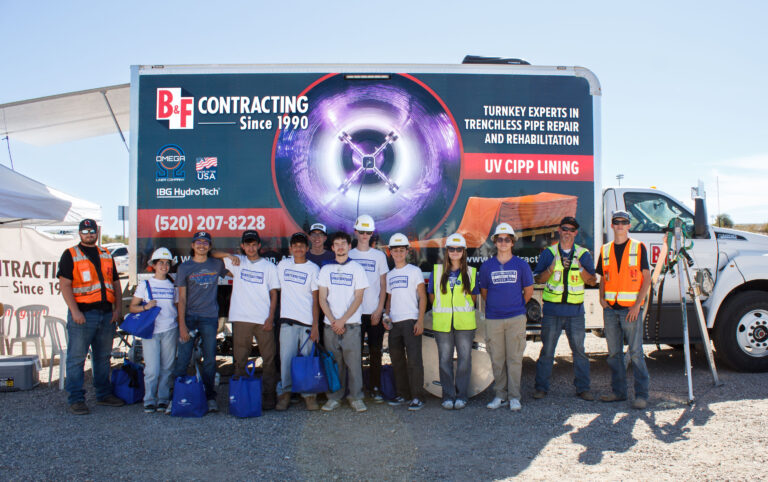 Construction workers and students standing in front of truck